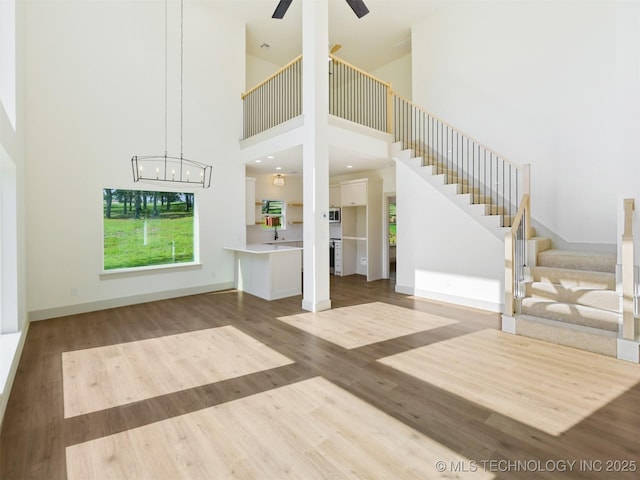 2 Valley View Dr, Burneyville, OK 73430 - unfurnished living room featuring stairway, a high ceiling, wood finished floors, a ceiling fan, and a chandelier