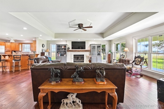 23535 E 720th Rd, Wagoner, OK 74467 - living room featuring a raised ceiling, ceiling fan, ornamental molding, dark wood-style floors, and a glass covered fireplace