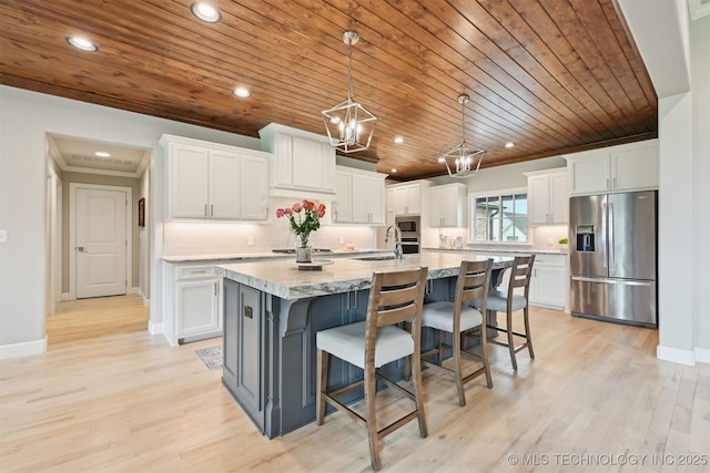 11325 S 212th E Ave, Broken Arrow, OK 74014 - kitchen featuring appliances with stainless steel finishes, wooden ceiling, white cabinets, a center island with sink, and a breakfast bar area