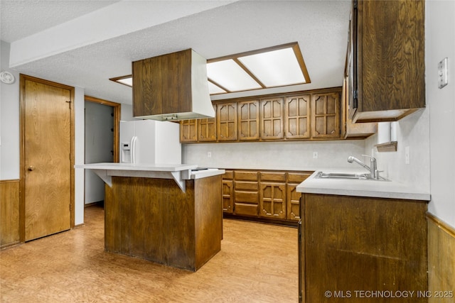 911 N Fir St, Jenks, OK 74037 - kitchen featuring white refrigerator with ice dispenser, brown cabinets, light countertops, glass insert cabinets, and a kitchen island