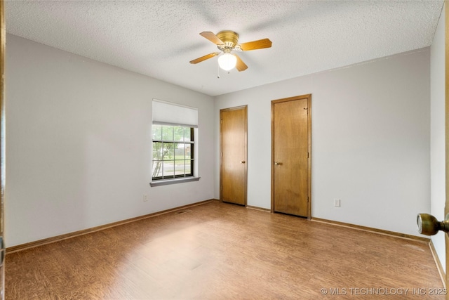 911 N Fir St, Jenks, OK 74037 - unfurnished bedroom featuring wood finished floors, two closets, a textured ceiling, and ceiling fan