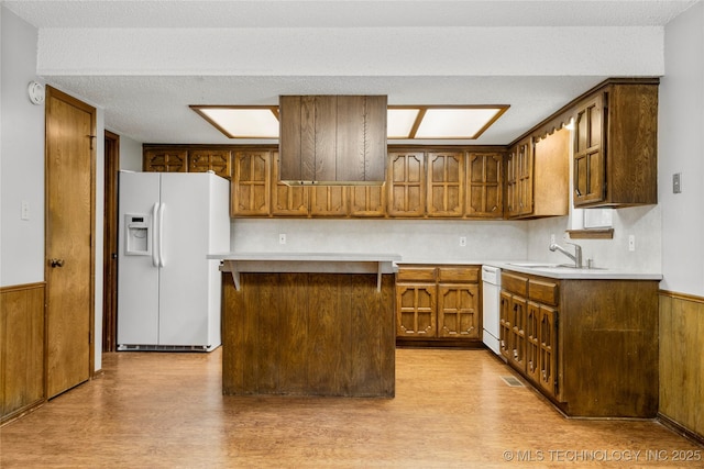 911 N Fir St, Jenks, OK 74037 - kitchen with white appliances, light wood-style flooring, light countertops, brown cabinets, and wood walls