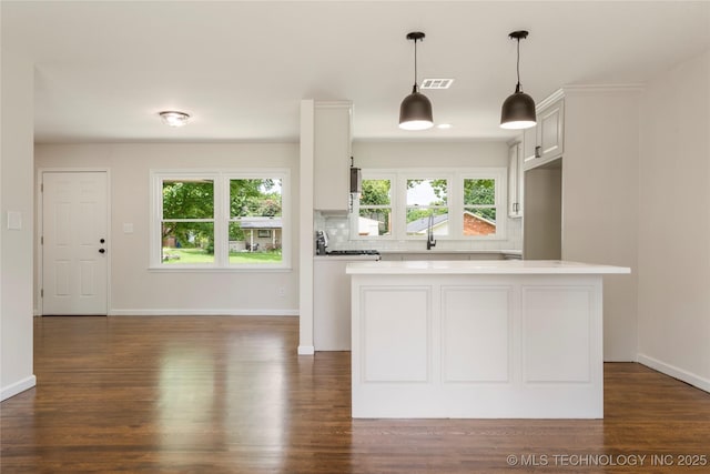 4015 S Urbana Ave, Tulsa, OK 74135 - kitchen featuring light countertops, tasteful backsplash, dark wood finished floors, decorative light fixtures, and white cabinets