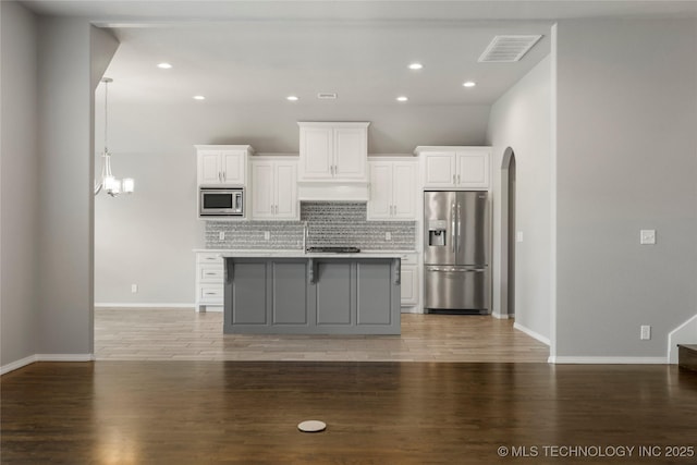 12913 S Ash St, Jenks, OK 74037 - kitchen with stainless steel appliances, tasteful backsplash, white cabinets, a kitchen island with sink, and arched walkways