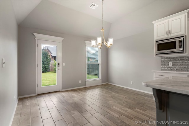 12913 S Ash St, Jenks, OK 74037 - kitchen with stainless steel microwave, a chandelier, vaulted ceiling, white cabinetry, and decorative light fixtures