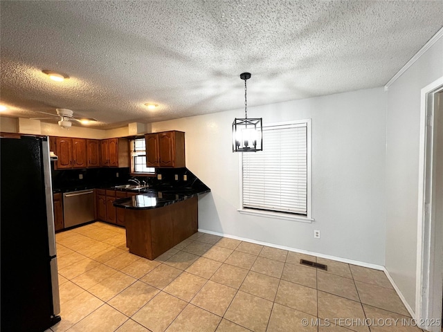 619 W 4th St, Skiatook, OK 74070 - kitchen with appliances with stainless steel finishes, a peninsula, dark countertops, light tile patterned floors, and a textured ceiling
