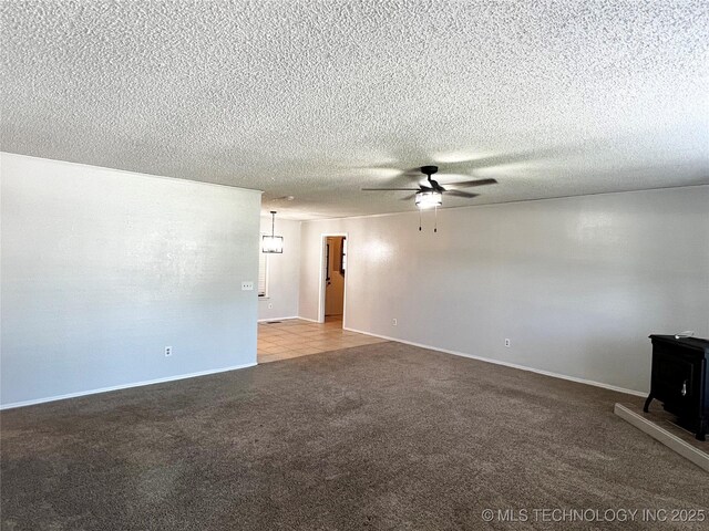 619 W 4th St, Skiatook, OK 74070 - carpeted spare room with a ceiling fan, a wood stove, and a textured ceiling