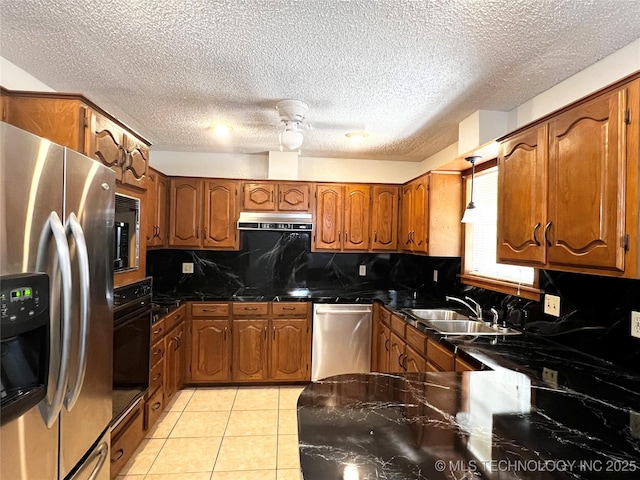 619 W 4th St, Skiatook, OK 74070 - kitchen featuring stainless steel appliances, under cabinet range hood, brown cabinetry, dark countertops, and a textured ceiling