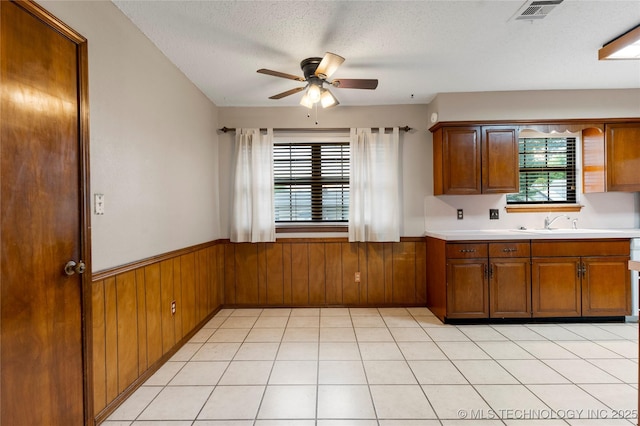 816 N Birch St, Jenks, OK 74037 - kitchen featuring ceiling fan, wainscoting, light countertops, wooden walls, and brown cabinets