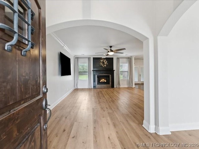 19345 S Fieldstone Dr E, Claremore, OK 74017 - unfurnished living room with ceiling fan, light wood-style flooring, a fireplace, arched walkways, and ornamental molding