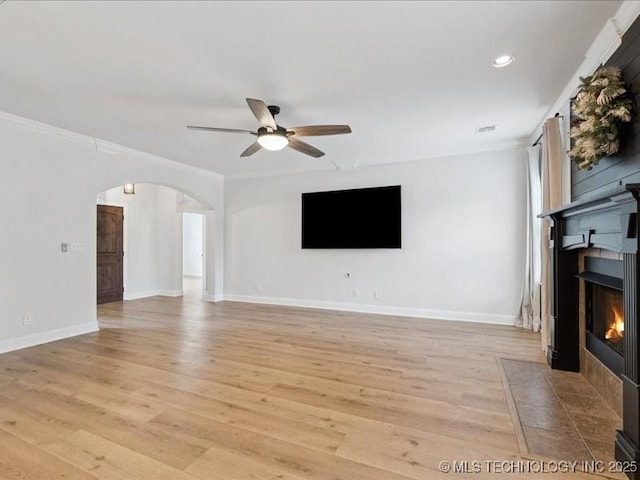 19345 S Fieldstone Dr E, Claremore, OK 74017 - unfurnished living room with a tiled fireplace, a ceiling fan, ornamental molding, arched walkways, and light wood-style flooring
