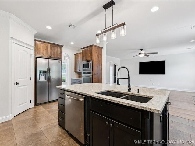 19345 S Fieldstone Dr E, Claremore, OK 74017 - kitchen featuring appliances with stainless steel finishes, a ceiling fan, arched walkways, open floor plan, and a kitchen island with sink