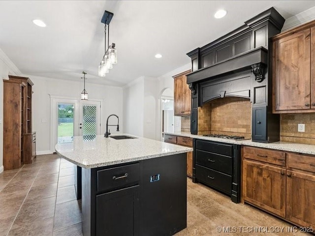 19345 S Fieldstone Dr E, Claremore, OK 74017 - kitchen featuring tasteful backsplash, crown molding, a kitchen island with sink, arched walkways, and pendant lighting