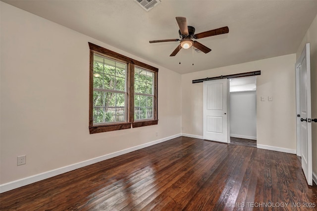 211 N 3rd St, Davis, OK 73030 - unfurnished bedroom with dark wood finished floors, a barn door, and ceiling fan