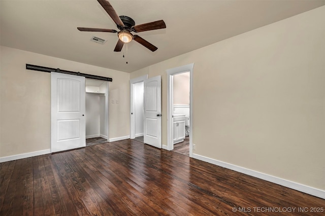 211 N 3rd St, Davis, OK 73030 - unfurnished bedroom with wood finished floors, a closet, a ceiling fan, a barn door, and connected bathroom