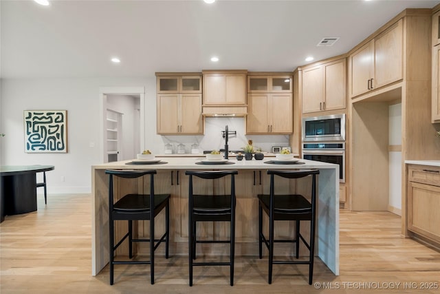 2048 E 128th Pl S, Jenks, OK 74037 - kitchen featuring stainless steel appliances, light brown cabinetry, glass insert cabinets, light wood-style flooring, and recessed lighting