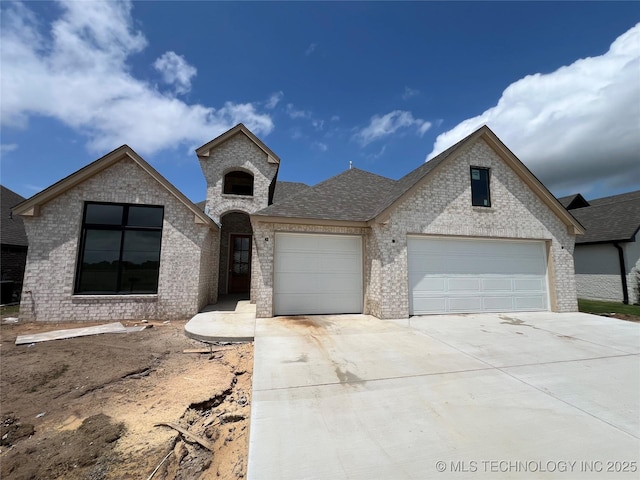 23191 E 107th St, Broken Arrow, OK 74014 - french country style house featuring brick siding, driveway, an attached garage, and a shingled roof