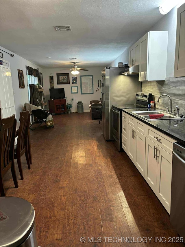 24 Lakeside, Adair, OK 74330 - kitchen featuring stainless steel appliances, under cabinet range hood, dark countertops, dark wood finished floors, and ceiling fan