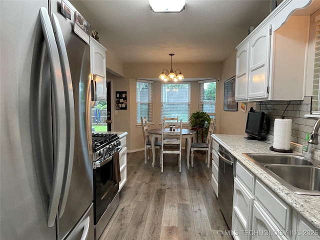3800 S Narcissus Ave, Broken Arrow, OK 74011 - kitchen with stainless steel appliances, white cabinets, tasteful backsplash, light wood-style flooring, and a chandelier