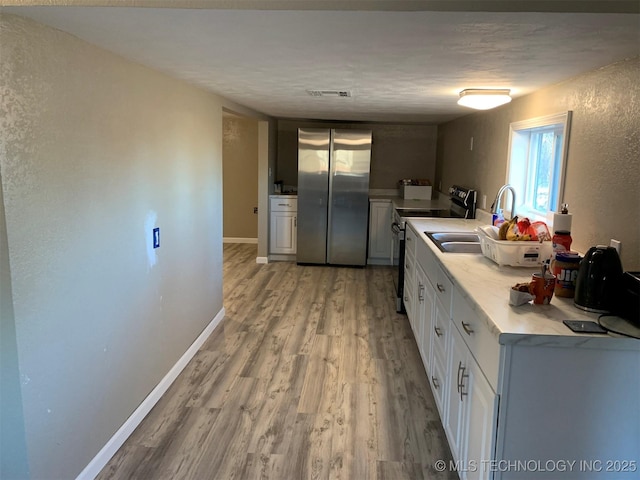 8201 State Highway 20, Eucha, OK 74342 - kitchen with freestanding refrigerator, range with electric cooktop, light wood-type flooring, light countertops, and white cabinetry