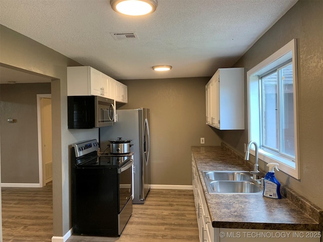8201 State Highway 20, Eucha, OK 74342 - kitchen featuring stainless steel appliances, wood finished floors, a textured ceiling, dark countertops, and white cabinets