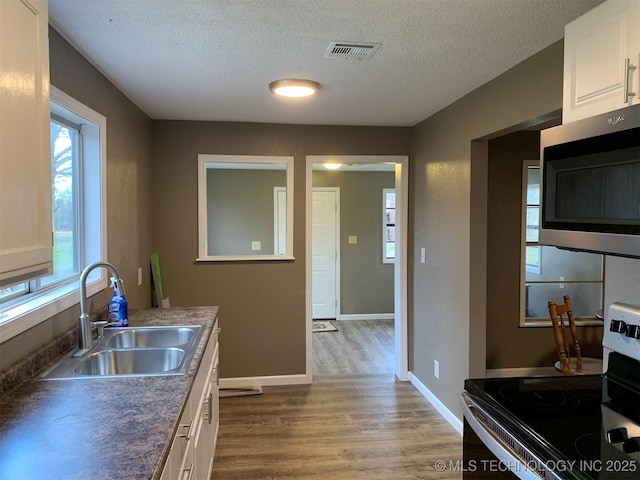 8201 State Highway 20, Eucha, OK 74342 - kitchen with stainless steel appliances, dark wood finished floors, white cabinetry, a textured ceiling, and dark countertops