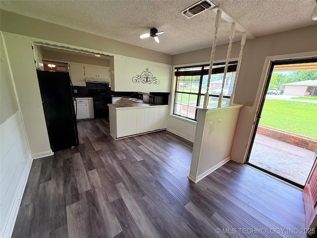 303 N 6th, Calera, OK 74730 - kitchen with black appliances, white cabinets, under cabinet range hood, a textured ceiling, and dark wood-type flooring