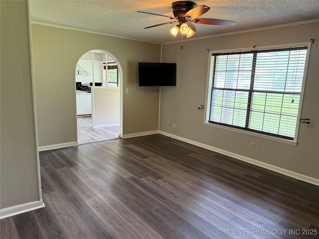 303 N 6th, Calera, OK 74730 - empty room featuring crown molding, dark wood-type flooring, arched walkways, ceiling fan, and a textured ceiling