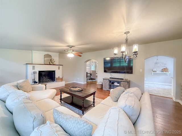 1312 S Oak, Ada, OK 74820 - living room with arched walkways, wood finished floors, a chandelier, a ceiling fan, and a fireplace