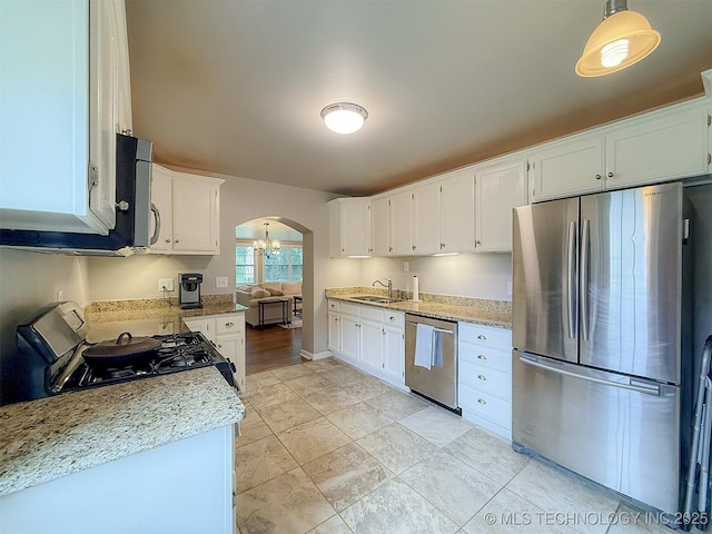 1312 S Oak, Ada, OK 74820 - kitchen featuring appliances with stainless steel finishes, arched walkways, white cabinetry, light stone countertops, and pendant lighting