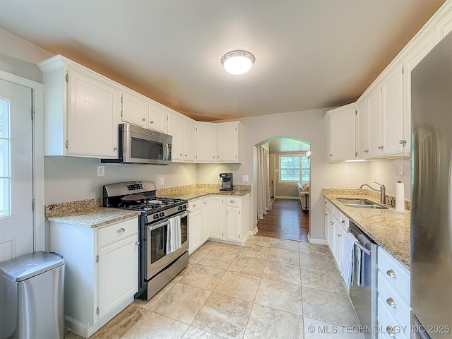 1312 S Oak, Ada, OK 74820 - kitchen with appliances with stainless steel finishes, arched walkways, light stone counters, and white cabinetry