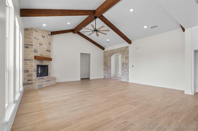 150 Chateau Bnd, Ardmore, OK 73401 - unfurnished living room featuring a ceiling fan, a fireplace, arched walkways, and light wood-type flooring