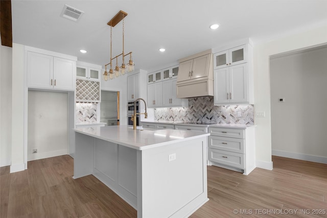 150 Chateau Bnd, Ardmore, OK 73401 - kitchen with backsplash, light countertops, custom range hood, light wood-type flooring, and recessed lighting