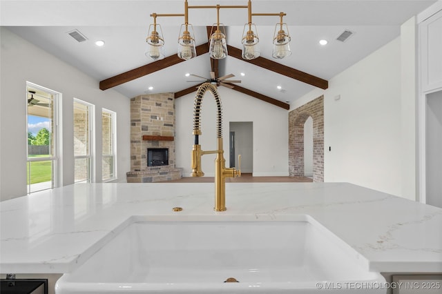 150 Chateau Bnd, Ardmore, OK 73401 - kitchen with open floor plan, a stone fireplace, light stone countertops, white cabinetry, and arched walkways