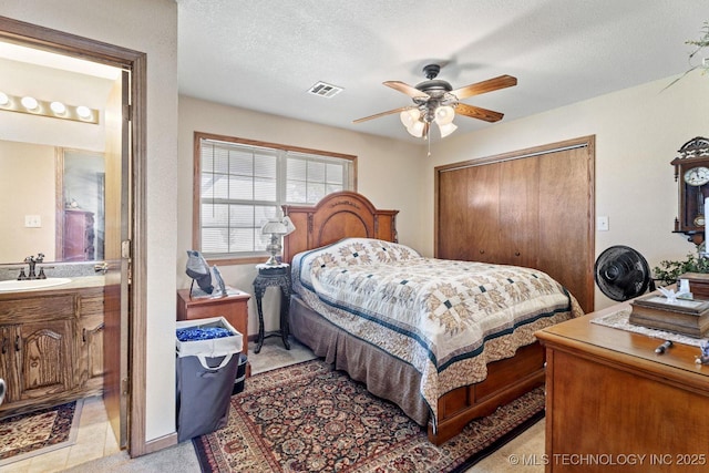 447247 E 70th Rd, Welch, OK 74369 - bedroom featuring a closet, ensuite bathroom, ceiling fan, a textured ceiling, and light colored carpet