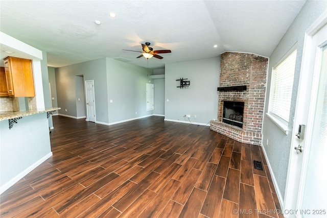 7224 NW 102nd, Oklahoma City, OK 73162 - unfurnished living room with a ceiling fan, lofted ceiling, dark wood-style floors, and a fireplace