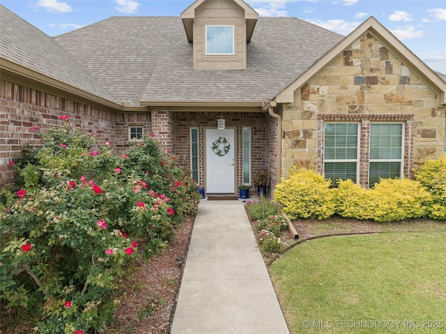 303 Hidden Path, Ardmore, OK 73401 - property entrance with a shingled roof, stone siding, brick siding, and a yard
