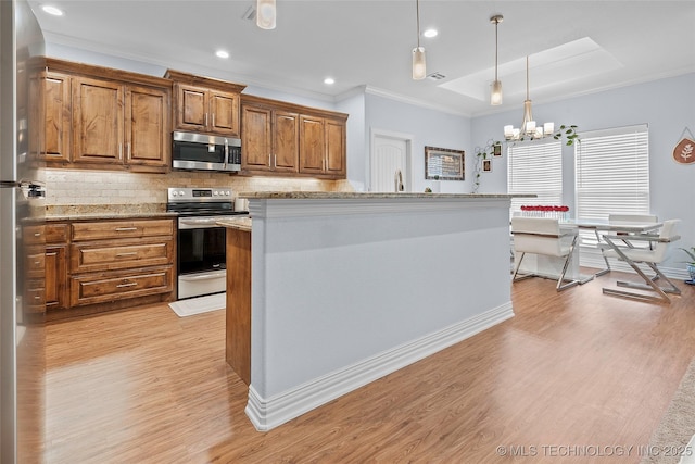 303 Hidden Path, Ardmore, OK 73401 - kitchen with stainless steel appliances, crown molding, a chandelier, brown cabinets, and light wood-type flooring