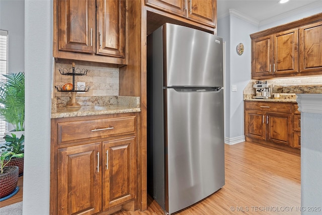 303 Hidden Path, Ardmore, OK 73401 - kitchen featuring freestanding refrigerator, tasteful backsplash, crown molding, light wood-type flooring, and light stone countertops