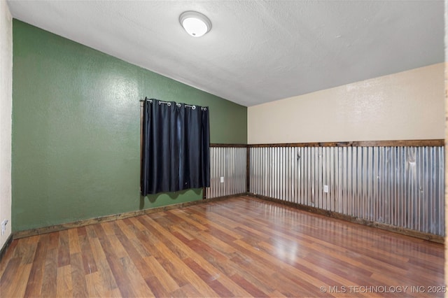 14820 Memorial, Wilson, OK 73463 - empty room with lofted ceiling, a textured wall, wood finished floors, and a textured ceiling