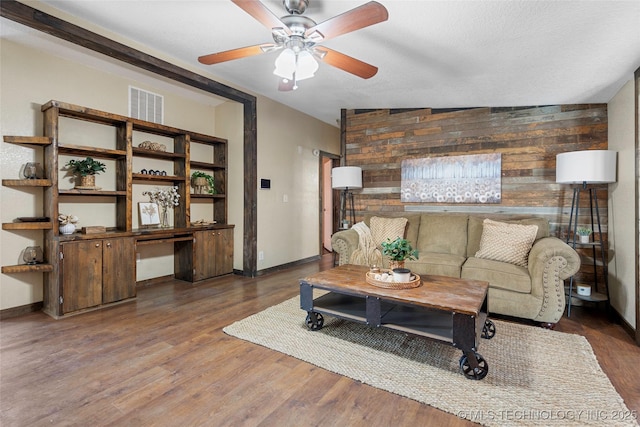 14820 Memorial, Wilson, OK 73463 - living area featuring wooden walls, a ceiling fan, wood finished floors, a desk, and an accent wall