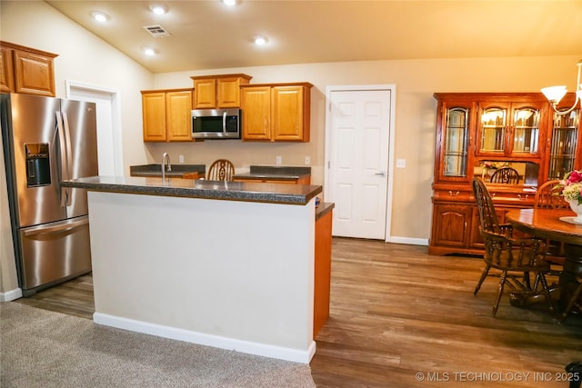 614 S Seminole St, Skiatook, OK 74070 - kitchen featuring appliances with stainless steel finishes, dark countertops, lofted ceiling, a kitchen island with sink, and dark wood-style floors
