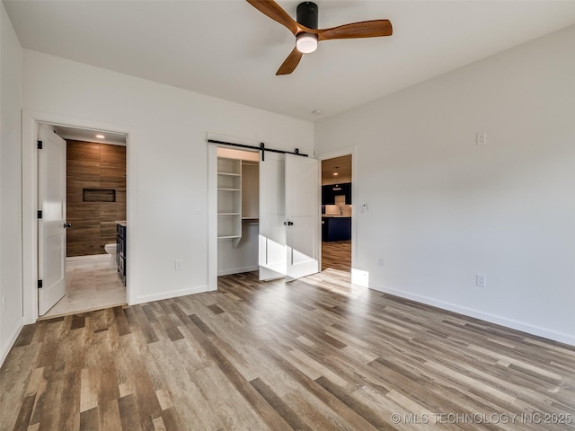 7 Port Duncan Blvd, Afton, OK 74331 - unfurnished bedroom featuring wood finished floors, a barn door, a walk in closet, ensuite bathroom, and a closet