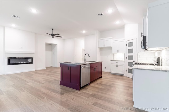 10917 S 271st E Ave, Coweta, OK 74429 - kitchen featuring stainless steel appliances, light wood-type flooring, ceiling fan, backsplash, and light stone countertops