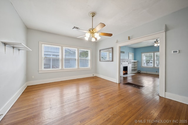 1414 E 8th St, Okmulgee, OK 74447 - unfurnished living room featuring ceiling fan, wood-type flooring, and a fireplace with flush hearth