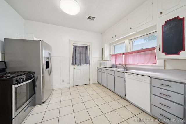 1414 E 8th St, Okmulgee, OK 74447 - kitchen with white appliances, light countertops, wainscoting, light tile patterned floors, and white cabinetry