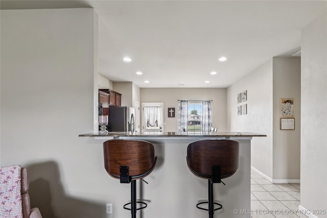 4661 E 148th St S, Bixby, OK 74008 - kitchen featuring stainless steel fridge, a kitchen breakfast bar, recessed lighting, light tile patterned flooring, and a peninsula