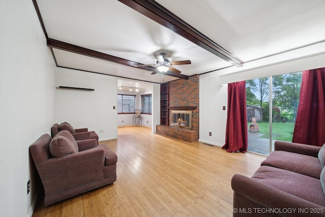 6922 E 16th St, Tulsa, OK 74112 - living area featuring beamed ceiling, a ceiling fan, light wood-style flooring, and a brick fireplace