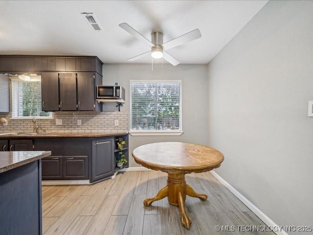 2346 S 118th E Ave, Tulsa, OK 74129 - kitchen featuring stainless steel microwave, healthy amount of natural light, light wood finished floors, and dark brown cabinets