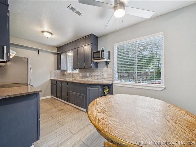 2346 S 118th E Ave, Tulsa, OK 74129 - kitchen with stainless steel microwave, refrigerator, light wood-type flooring, ceiling fan, and backsplash